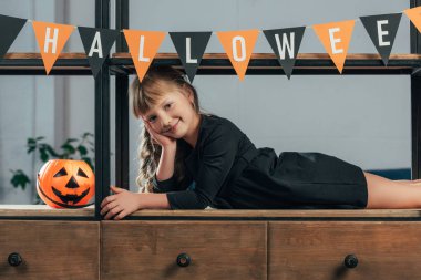 Cadılar Bayramı için dekore edilmiş oda kamerada bakarak gülen çocuk portresi