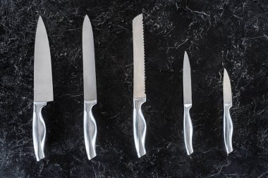 siyah yüzey üzerinde düzenlenmiş farklı mutfak bıçaklar üstten görünüm 