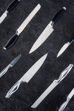 top view of various kitchen knives arranged on black surface, seamless pattern clipart
