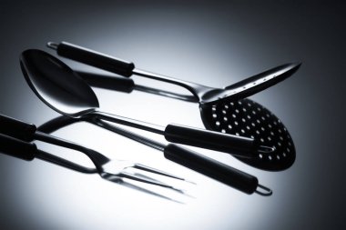 close-up view of colander, fork with two tines and ladle on grey clipart