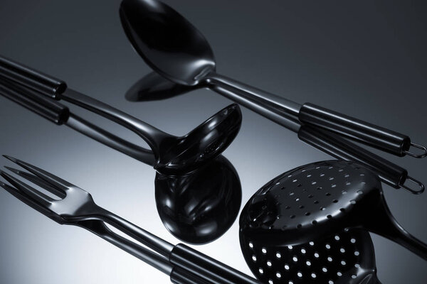 close-up view of shiny stainless steel utensils reflected on grey