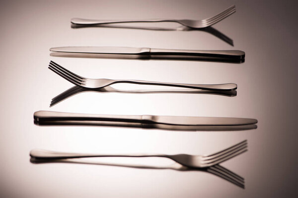 close-up view of shiny forks and knives arranged on grey   