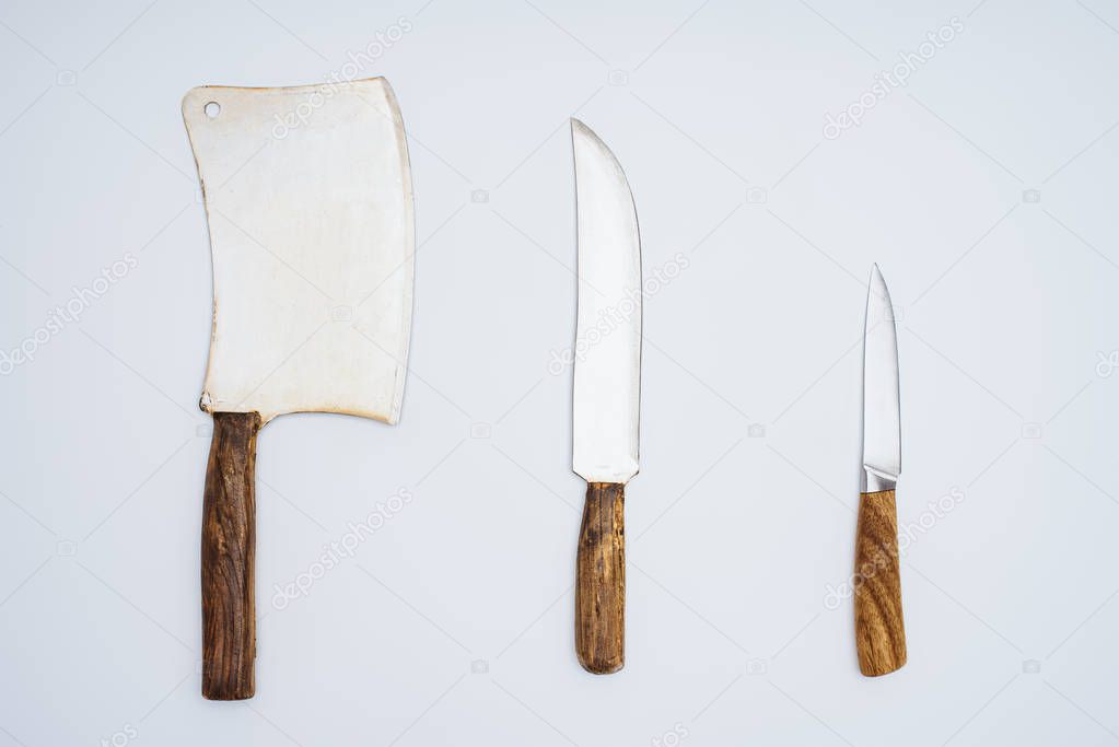 top view of cleaver and kitchen knives with wooden handles isolated on grey 