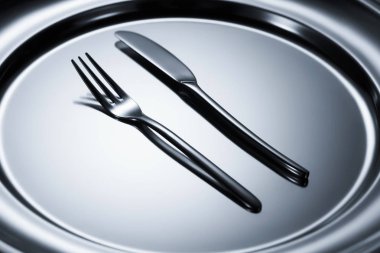 çatal ve bıçak üzerinde parlak metal tepsi düzenlenmiş yakından görmek 