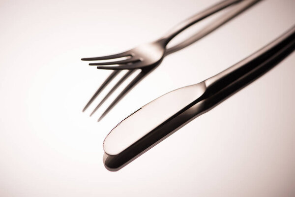 close-up view of shiny fork and knife reflected on grey