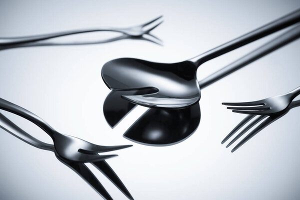 close-up view of shiny stainless steel cutlery reflected on grey