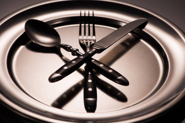 close-up view of cutlery arranged on shiny metal tray on grey 