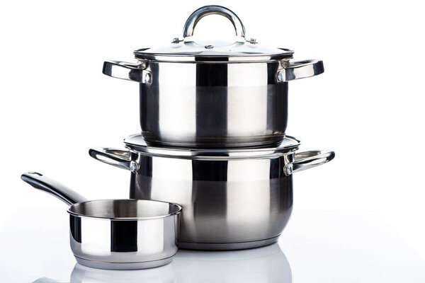 close-up view of shiny stainless steel pots and pans on white 