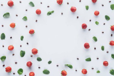top view of round frame made of ripe strawberries with mint leaves and coffee beans on white surface clipart