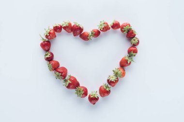 top view of heart shape sign made of fresh strawberries on white surface clipart