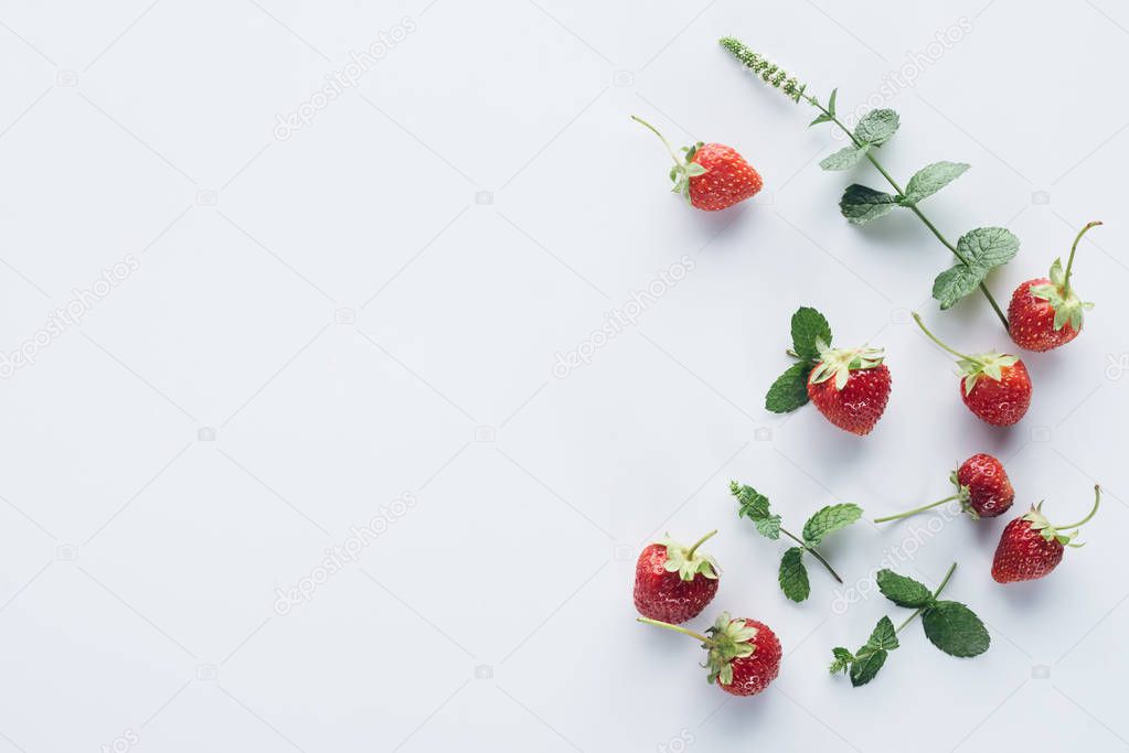 top view of fresh strawberries with mint leaves on white surface