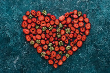 top view of heart sign made of ripe strawberries on blue concrete surface clipart