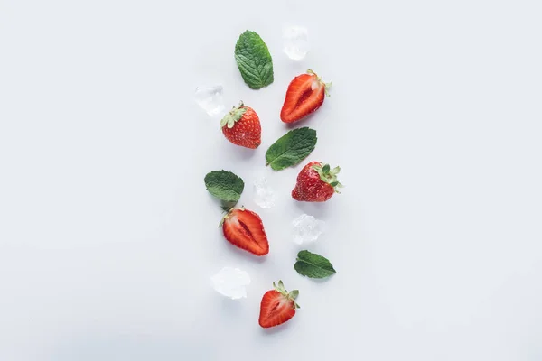 白色表面的薄荷叶和冰块的成熟减半草莓的最高视图 — 图库照片