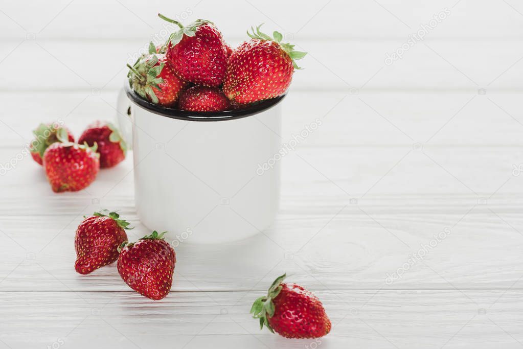 mug of ripe strawberries on white wooden tabletop