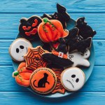 Elevated view of plate with spooky homemade halloween cookies on wooden table