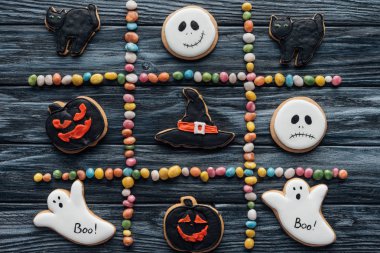 top view of composition from colorful candies and arranged halloween cookies on wooden table  clipart