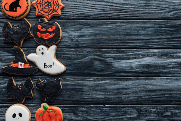 elevated view of arranged halloween homemade cookies placed in rows on black wooden background 