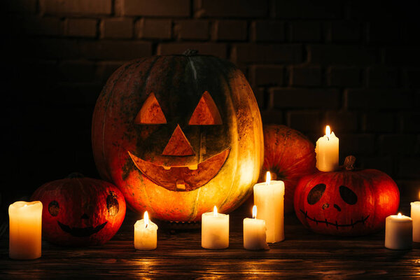 halloween carved pumpkins on wooden table in front of brick wall 