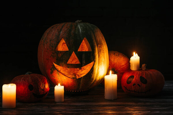 spooky halloween carved pumpkins with candles on wooden table on black background