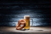Glas frisches Bier und leckere Brezel auf Holztisch, Oktoberfest-Konzept