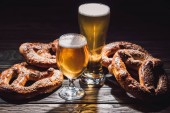 two glasses of beer and yummy pretzels on wooden table, oktoberfest concept