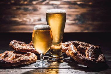 İki bardak bira ve ahşap masa, oktoberfest kavramı üzerinde lezzetli simit