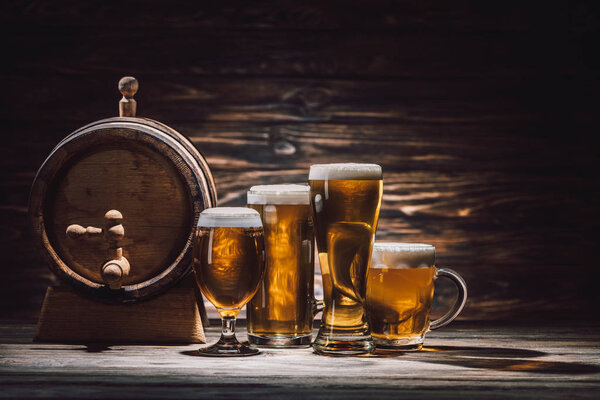 tasty beer in glasses and beer barrel on wooden tabletop, oktoberfest concept