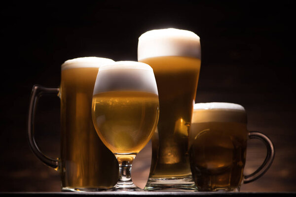 четыре бокала свежего пива на деревянном столе, концепция фестиваля Октоберфест
