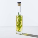 Bottle of natural herbal essential yellow oil with twig on white cube