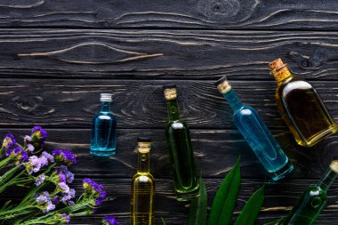 renkli şişe doğal bitkisel yağlar ve ahşap yüzey üzerinde mor çiçekler 