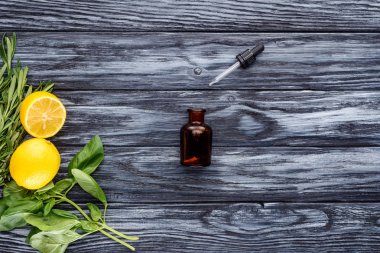 şişe doğal bitkisel uçucu yağ, Damlalık ve limon üstten görünüm ahşap masa üzerinde