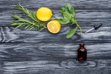 elevated view of bottle of natural herbal essential oil, dropper and lemons on wooden table
