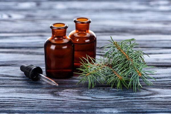 bottles of natural herbal essential oils, fir twigs and pipette on wooden table