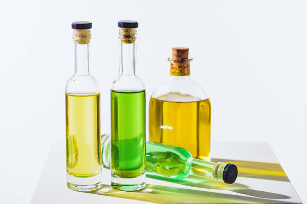 bottles of natural herbal essential green and yellow oils with corks on white surface