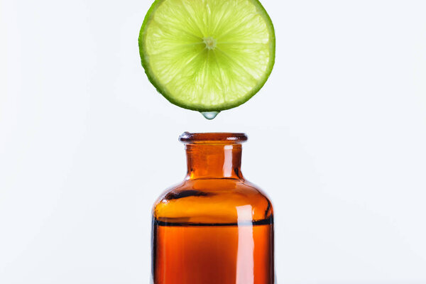 ароматический сок известь кусок капает в бутылку натуральных травяных эфирное масло изолированы на белом
