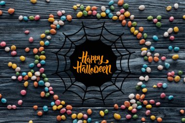 circle made of colorful delicious candies on wooden background with spider web and 