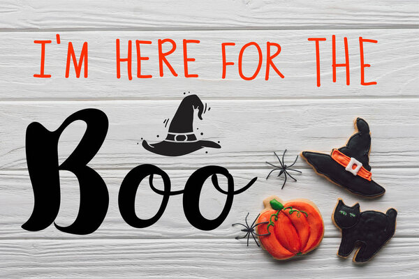 elevated view of tasty homemade halloween cookies on wooden background with "Im here for the Boo" lettering
