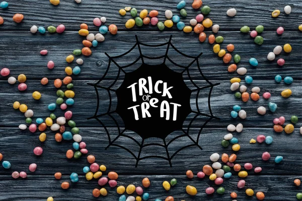 Circle made of colorful delicious candies on wooden background with spider web and "trick or treat" lettering — Stock Image Circle Made Colorful Delicious Candies Wooden Background Spider Web Trick Stock Image
