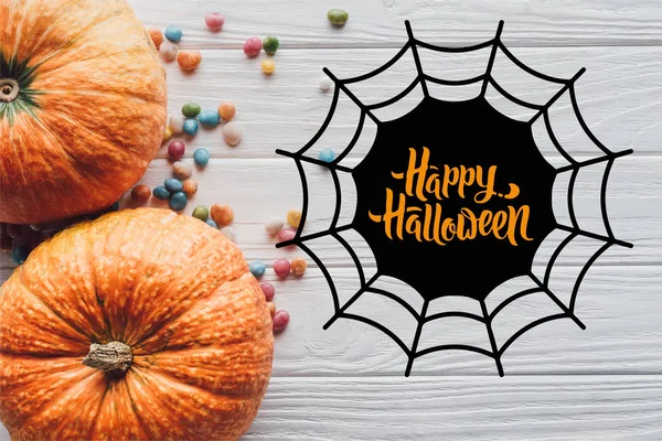 Top view of pumpkins and colorful candies on wooden background with spider web and "happy halloween" lettering — Stock Image Top View Pumpkins Colorful Candies Wooden Background Spider Web Happy Stock Image