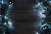 pohled shora na vánoční stromeček větvičky s šišky, cetky a osvětlené věnec na dřevěné pozadí
