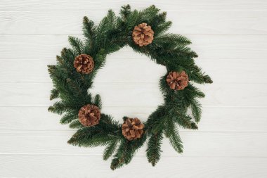 close-up view of beautiful christmas wreath with pine cones on white wooden background  clipart