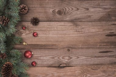top view of shiny balls, coniferous twigs and pine cones on wooden background  clipart