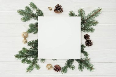 yaprak dökmeyen çalı çırpı, çam kozalakları ve altın Noel topları ile boş beyaz kartı üstten görünüm