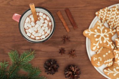 top view of cup with hot chocolate and marshmallows, cinnamon sticks and gingerbread cookies  clipart