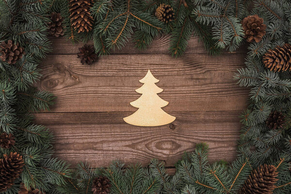 top view of beautiful christmas tree symbol and coniferous branches with pine cones on wooden background