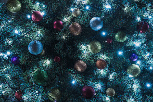 close-up view of beautiful christmas tree with colorful balls and illuminated garland  