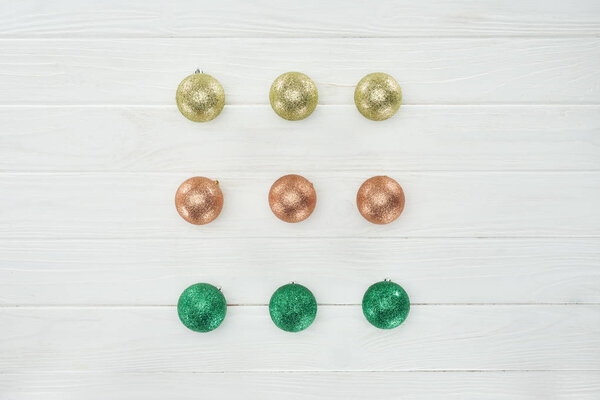 верхний вид красивых блестящих рождественских шаров на белой деревянной поверхности
 