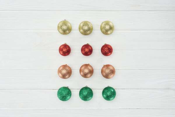 Верхний вид красивых ярких красочных рождественских шаров на белой деревянной поверхности
 