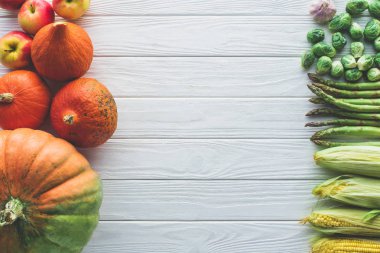 ahşap masa üzerinde Brüksel lahanası, yeşil kuşkonmaz, Mısır koçanı, sarımsak ve kabaklar üstten görünüm 