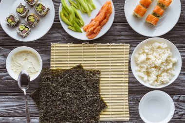 üstten görünüm nori yaprak ve tahta masada lezzetli sushi hazırlanması için malzemeler